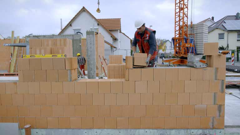 Ein Maurer errichtet die Ausstand eines Einfamilienhauses.
